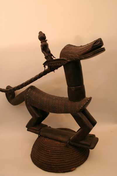 Bambara (tji-wara), d`afrique : Mali, statuette Bambara (tji-wara), masque ancien africain Bambara (tji-wara), art du Mali - Art Africain, collection privées Belgique. Statue africaine de la tribu des Bambara (tji-wara), provenant du Mali, 1099/4175.Grand cimier zoomorphe Tji-wara, porté par les membres de la même société. Ces cimiers étaient portés lors des cérémonies agricoles.Içi une antilope stylisée avec une tête allongée 18cm.,et une queue de caméléon,dans une position prêt à sauter,en emportant sur ses longues cornes un bonhomme debout.Le masque est fixé sur un socle heaume fait en vannerie. H.12cm. Masque avec une belle patine et  d